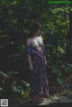 A woman in a long dress standing in the woods.