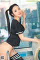 A woman in a black shirt and stockings posing for a picture.