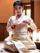 A woman in a white and red hanbok sitting on the floor.