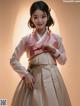 A woman in a pink and white hanbok is posing for a picture.