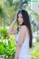 A woman in a white tank top posing for a picture.