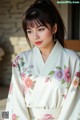 A woman wearing a white kimono with pink flowers on it.