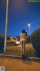 A woman walking down a street at night. 