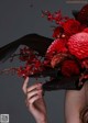 A woman holding a bouquet of red flowers in her hands.