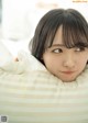 A young woman laying in bed with a pillow.