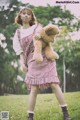 A woman in a red and white dress holding a teddy bear.