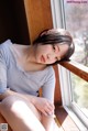 A woman sitting on a window sill looking out the window.