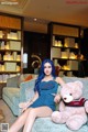 A woman sitting on a couch with a teddy bear.