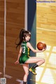 A woman in a green and yellow uniform holding a basketball.